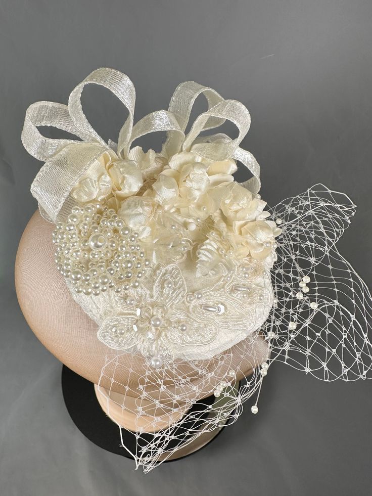 Cute mini cream bridal fascinator.  Adorned with tiny roses. Appliqués, pearl brooch, ribbon and veiling.  Attached with large clip Elegant Cream Fascinator For Vintage Events, Elegant Wedding Headpiece With Flower Decoration, Elegant Floral Wedding Headpieces, Elegant Wedding Fascinator With Flower Decoration, Elegant Flower-shaped Fascinator For Weddings, Elegant Handmade Flower Hair Accessories For Formal Events, Elegant Handmade Flower Hair Accessories For Formal Occasions, Elegant Cream Flower Fascinator, Elegant Flower Hair Accessories For Wedding