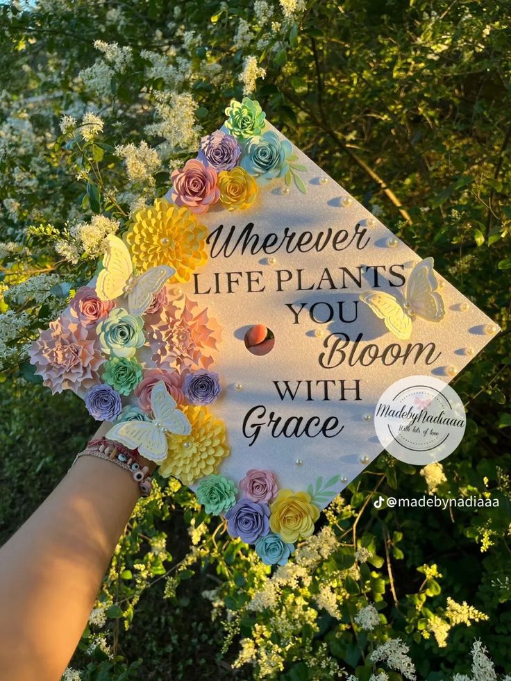 someone holding up a graduation cap with flowers on it that says, wherever life plants you bloom with grace