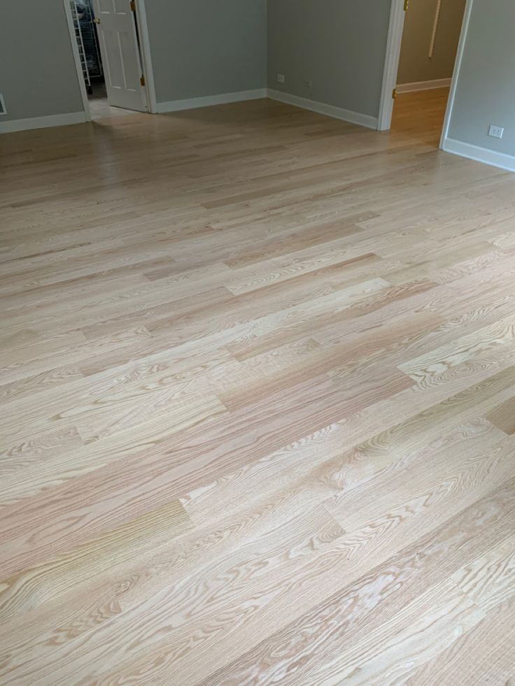 an empty room with hard wood flooring and white trim on the walls, doors and windows