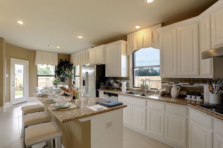 a kitchen filled with lots of white cabinets and counter top space next to a dining room table