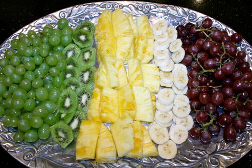 a platter with grapes, bananas, kiwis and other fruit on it