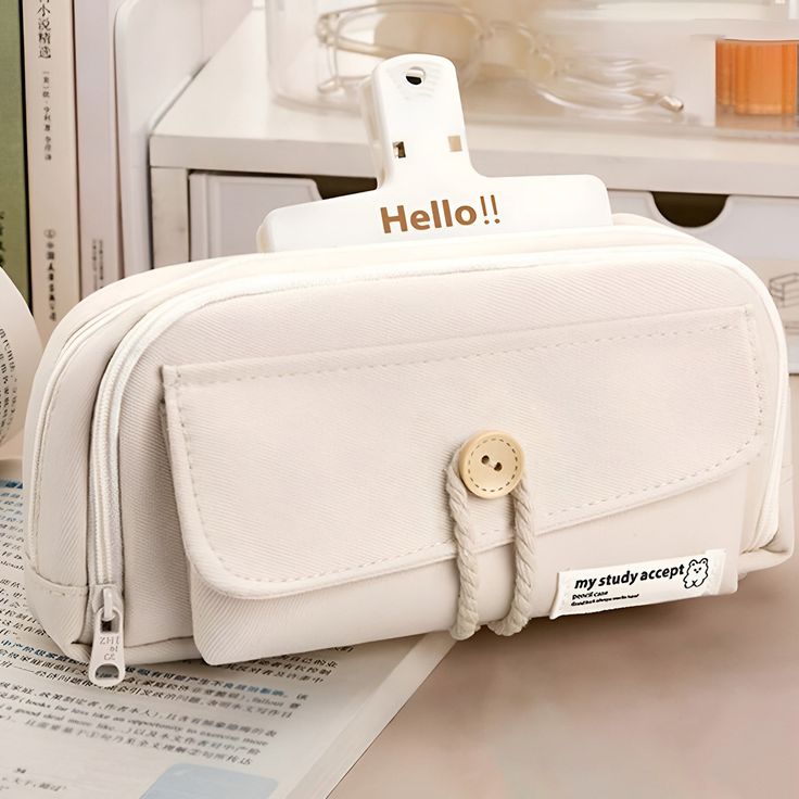 a white purse sitting on top of a table next to a stack of books and other items