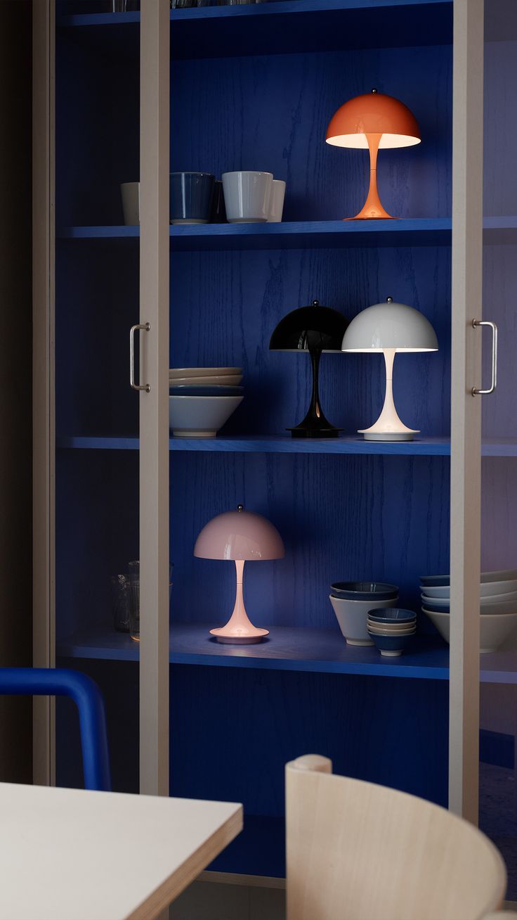 a blue bookcase filled with lots of different types of lamps and plates on top of it