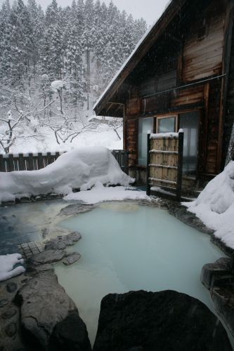 an outdoor hot tub surrounded by snow covered rocks