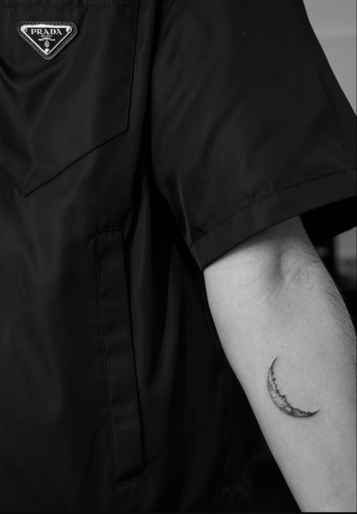 a black and white photo of a person's arm with a crescent tattoo on it