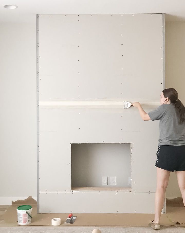 a woman is painting the walls in a room with white paint and she is using a roller