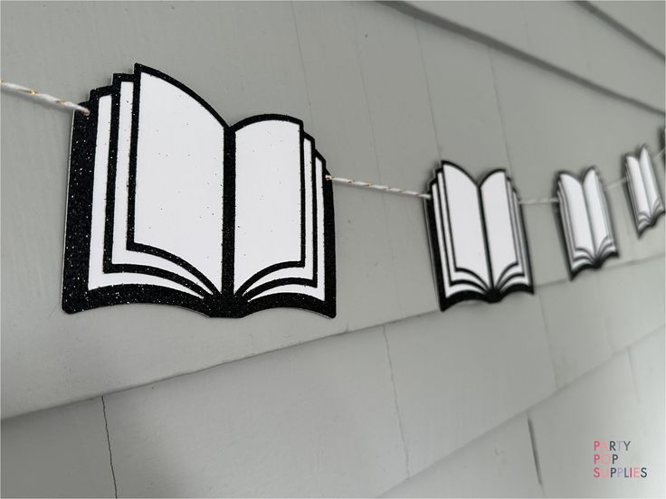 an open book is hanging on a line with clothes pins in the shape of books