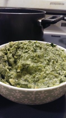 a white bowl filled with green food on top of a stove