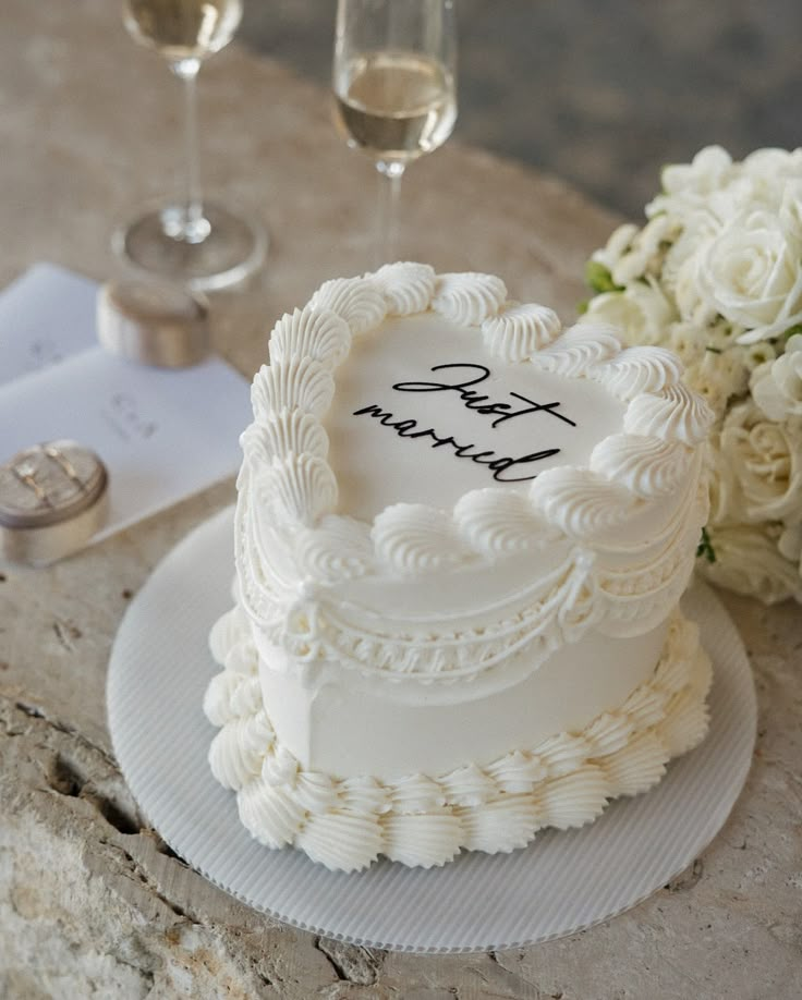 a wedding cake sitting on top of a table next to some wine glasses and flowers