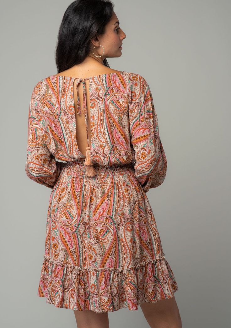 An ultra-flattering and versatile mini dress is a must for spring, summer and fall. This bohemian style is designed in a vintage-inspired orange paisley print, featuring voluminous long sleeves, a flirty surplice v-neckline, and a ruffle-trimmed tiered skirt. The open back with tie closure adds a breezy and playful touch. Paisley print Relaxed fit Long volume sleeve Elastic wrist cuff Mini length Ruffle-trimmed tiered skirt Surplice v-neckline Smocked elastic waist Back keyhole with tassel tie c Flowy Long Sleeve Dresses With Paisley Print, Orange Long Sleeve Boho Dress, Orange Long Sleeve Bohemian Dress, Fall Paisley Print V-neck Mini Dress, Fall V-neck Mini Dress With Paisley Print, Spring Long Sleeve Mini Dress With Paisley Print, Chic Long Sleeve Mini Dress With Paisley Print, Long Sleeve Boho Dress With Paisley Print, Chic Long Sleeve Paisley Print Mini Dress