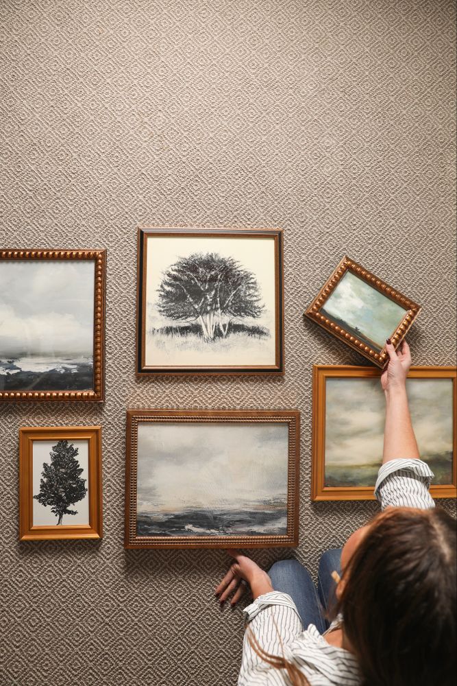 a woman is pointing at pictures on the wall with her hand in front of them