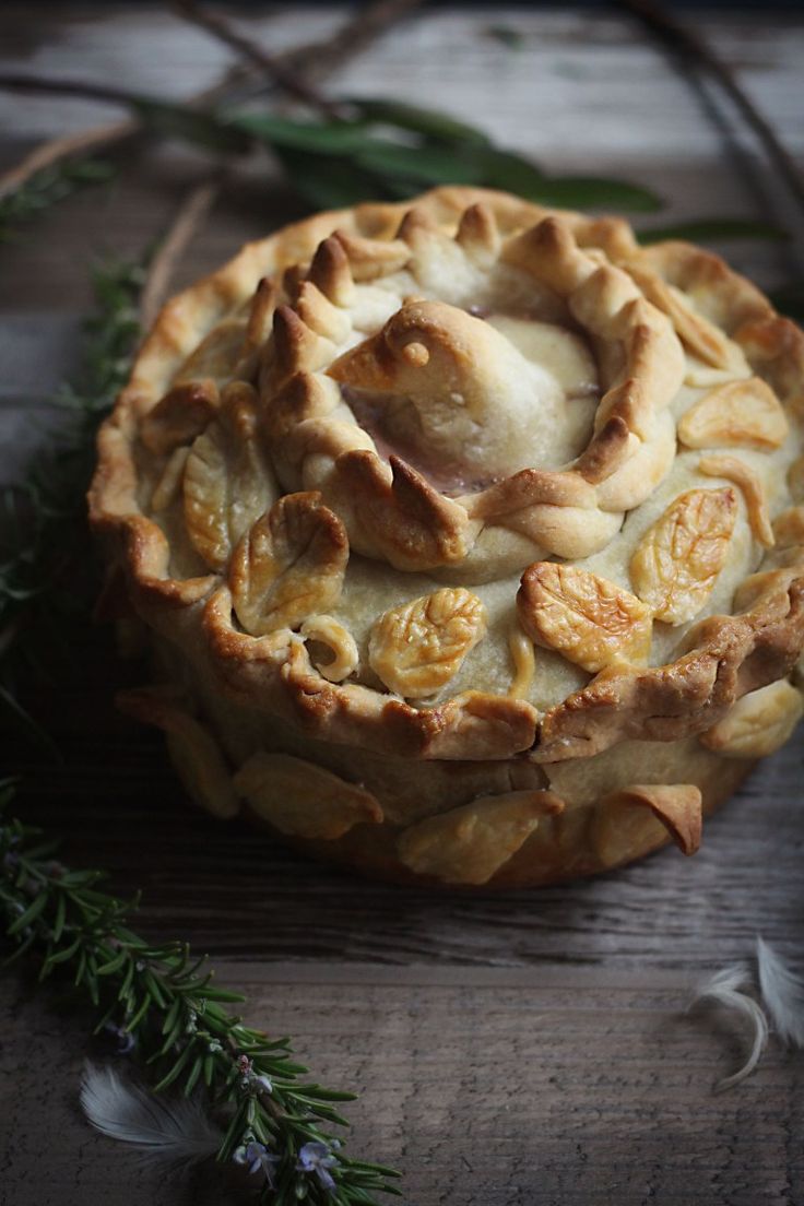 a pie sitting on top of a wooden table next to some leaves and twigs,