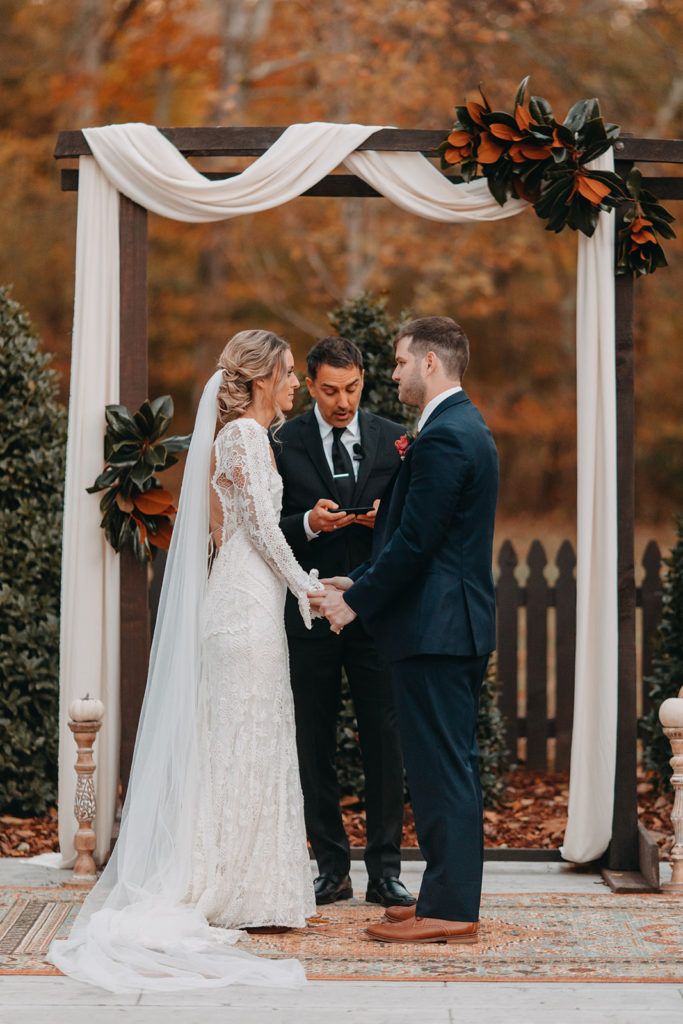 a bride and groom exchanging vows under an arch