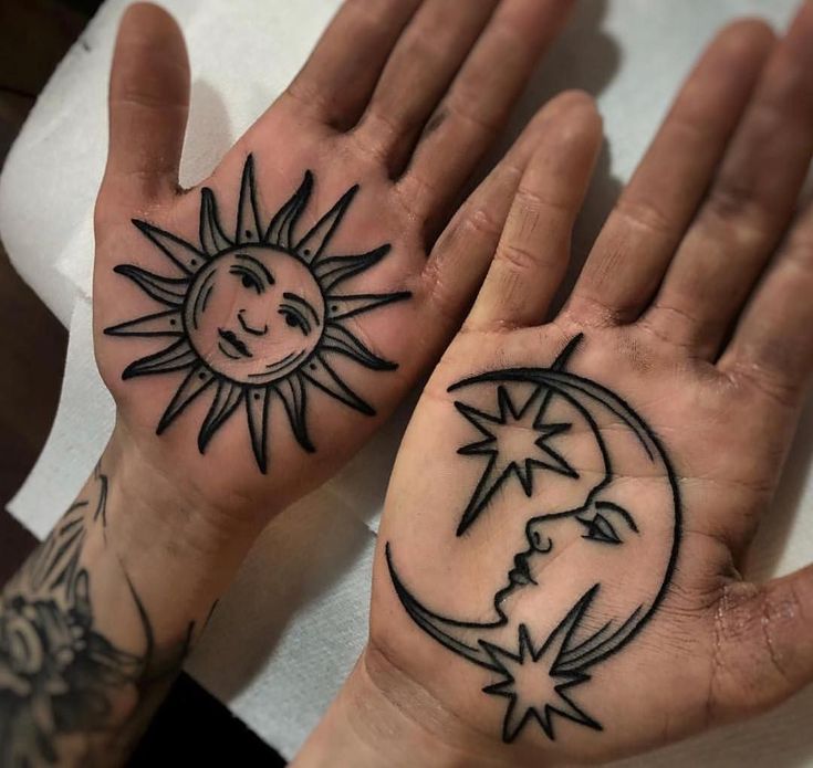 two hands with sun and moon tattoos on them