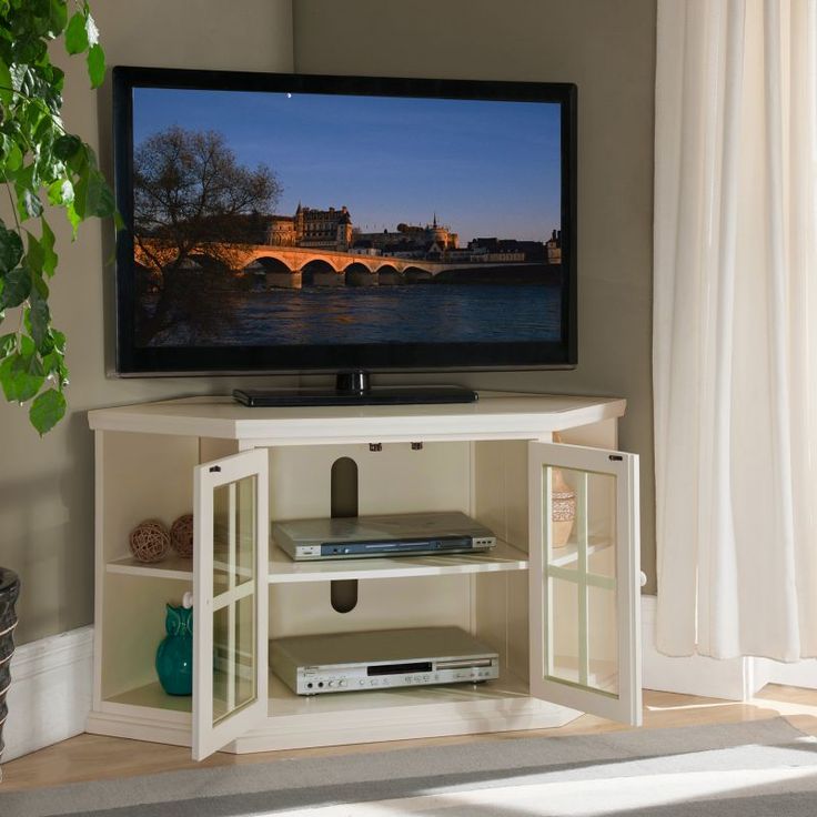 a flat screen tv sitting on top of a white entertainment center next to a window