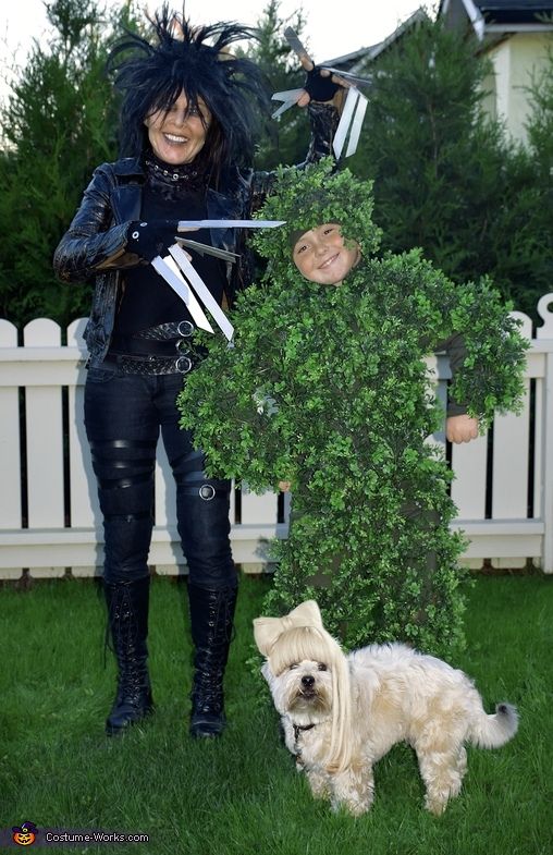 a woman in black outfit standing next to a white dog and holding two knifes