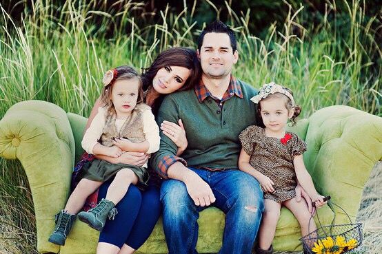 a man and two children sitting on a green couch in front of some tall grass