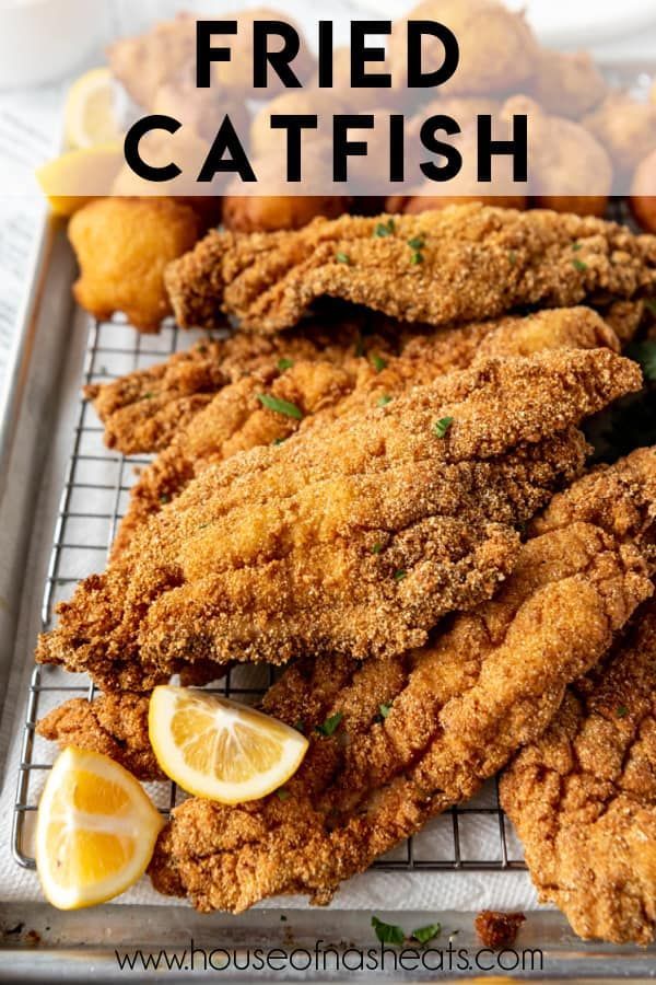 fried fish on a cooling rack with lemon wedges