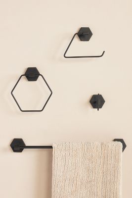 three black hexagonal hooks on the wall above a towel