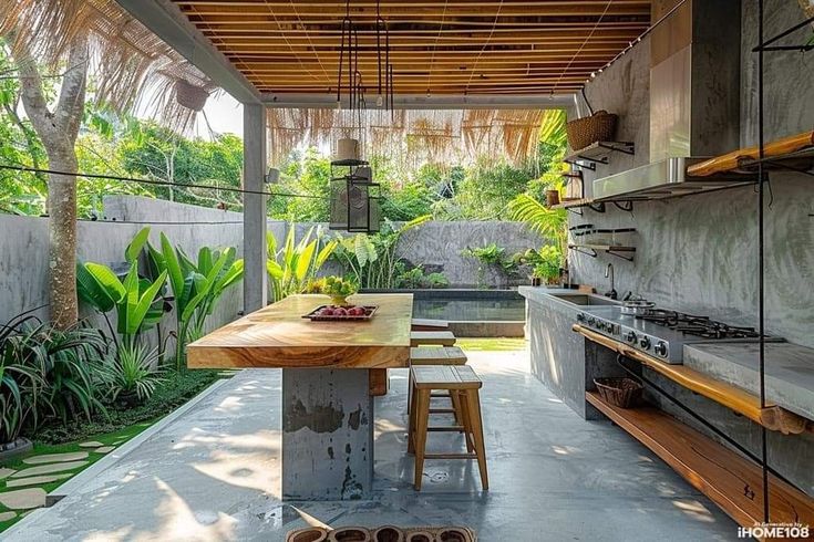 an outdoor kitchen with wooden counter tops and stools next to a table that is surrounded by greenery