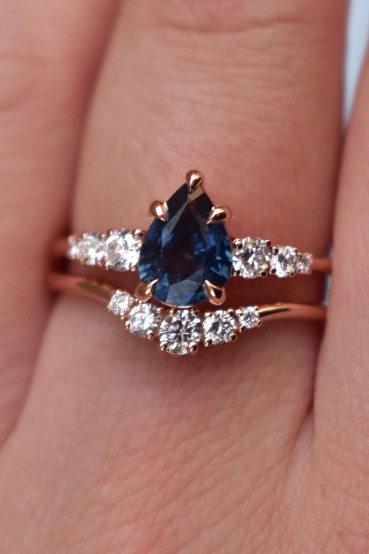 a woman's hand holding a blue and white diamond ring