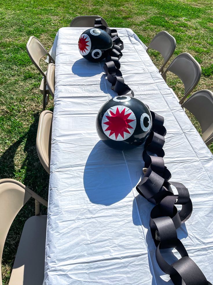 a long table topped with black and white decorations on top of a grass covered field