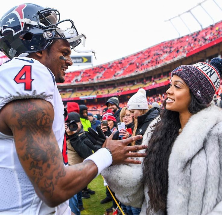 a man and woman standing next to each other at a football game