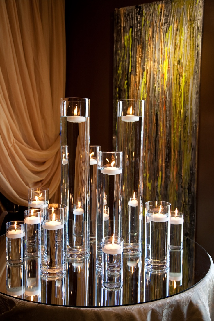 a table topped with lots of clear vases filled with candles