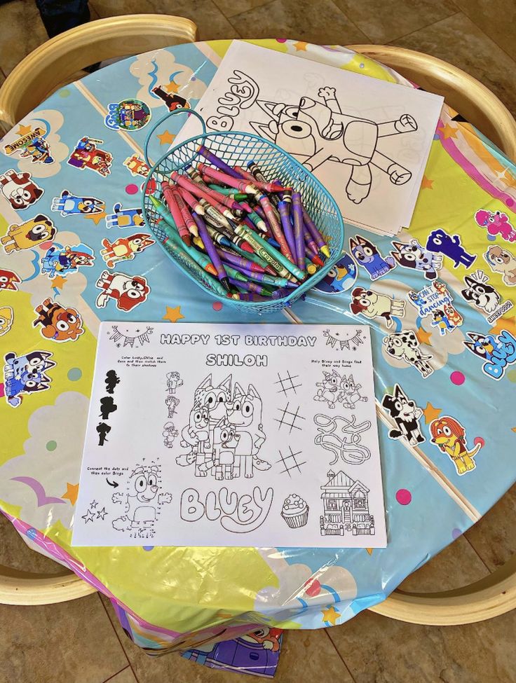 a basket full of colored pencils sitting on top of a table next to a coloring book