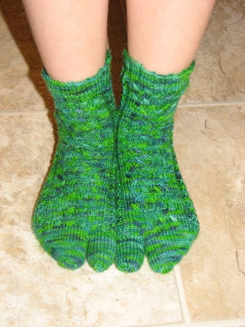 the legs of a woman wearing green knitted socks on tiled floor next to white tile