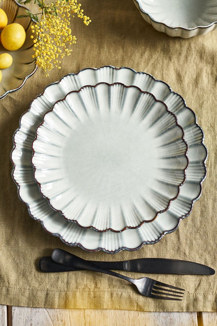 an empty white plate and silverware on a table cloth with yellow flowers in the background