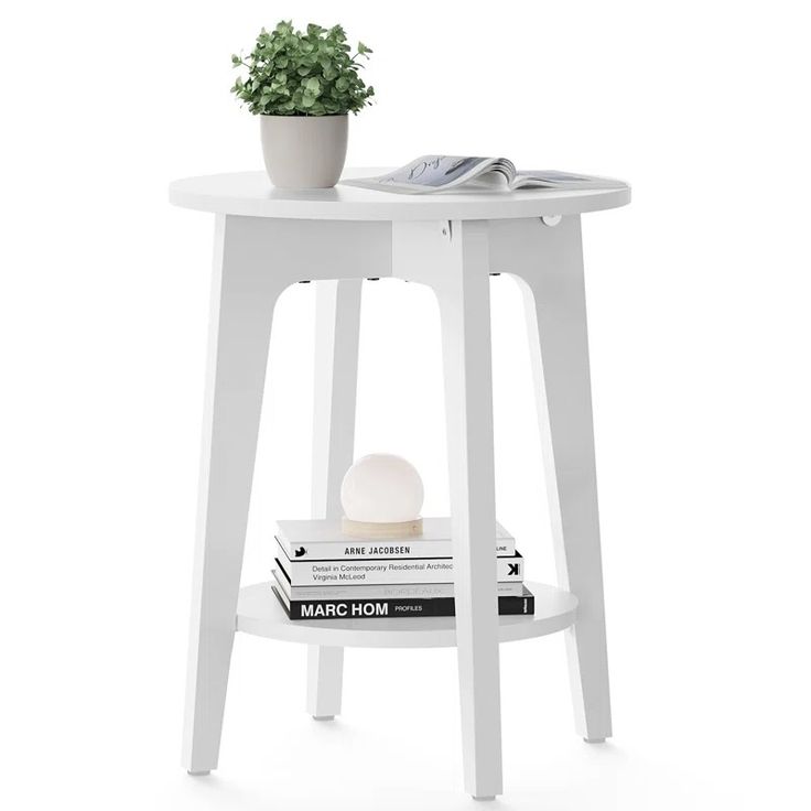 a white table with a plant on top and books under it, next to a phone