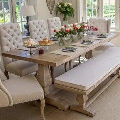 a dining room table and bench with flowers in vases on the top one side