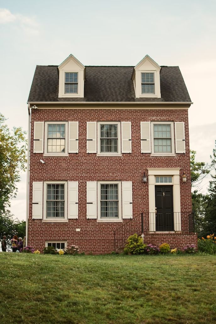 a large brick house with white shutters on the front and two storyed windows