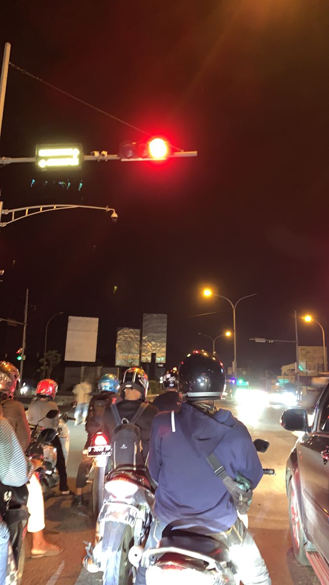 a group of motorcyclists waiting at a traffic light