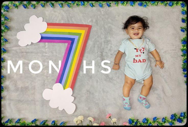 a baby laying on top of a blanket next to a rainbow