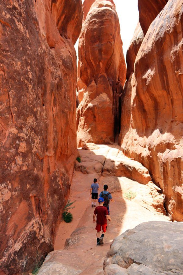 two people are walking through the narrow canyon