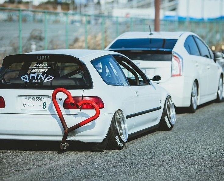 two white cars parked next to each other on the side of a road with graffiti written on them