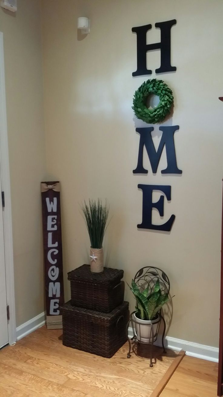 there is a welcome sign on the wall next to some baskets and a potted plant