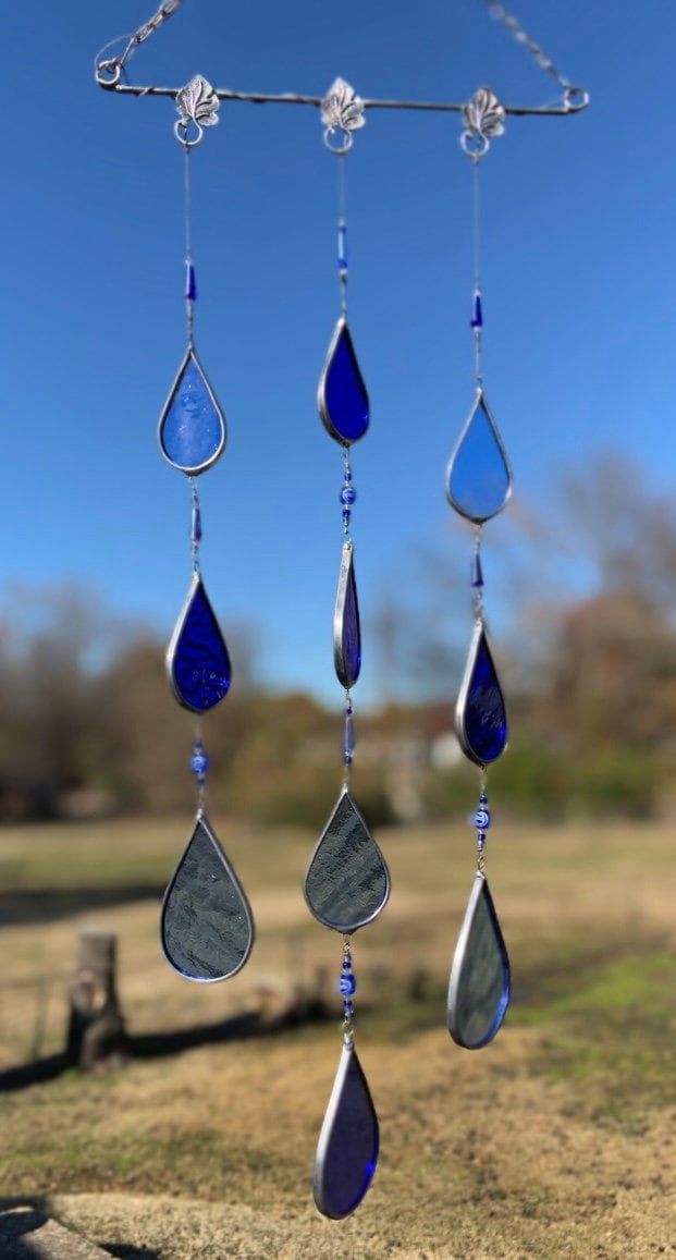 a wind chime with blue and silver tears hanging from it's side