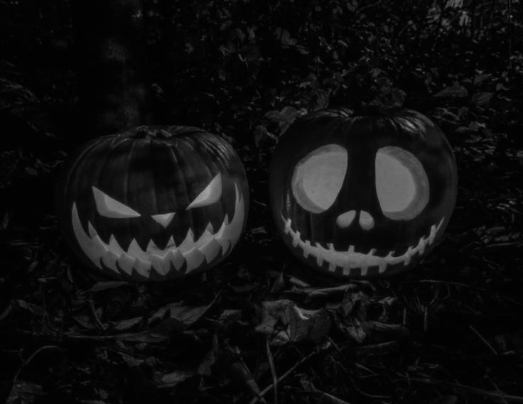 two jack o lantern pumpkins sitting on the ground with their faces carved into them