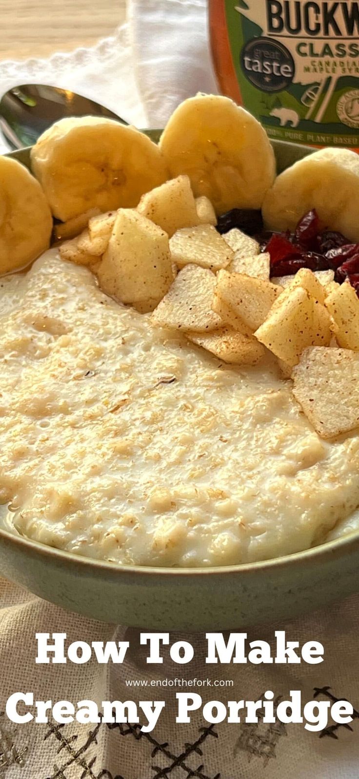 a bowl of creamy porridge with bananas and cranberries in the center on a table