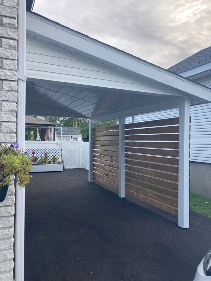 a car is parked in front of a house with a wooden fence on the side