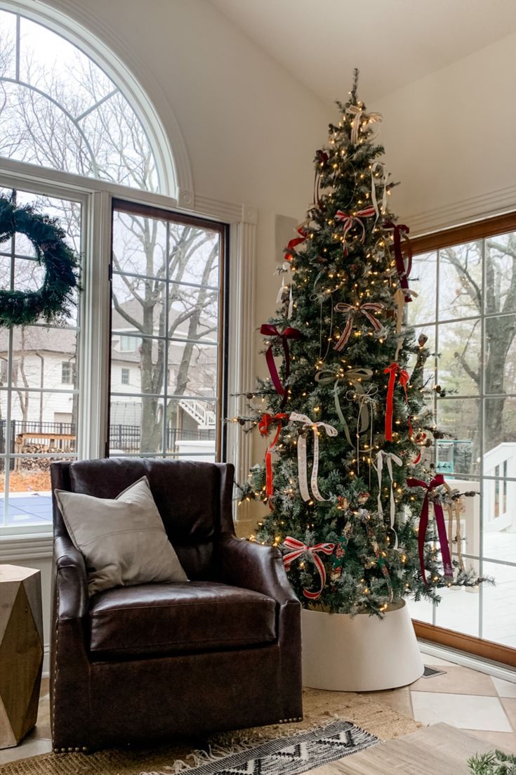 a living room with a christmas tree in the corner and a chair next to it