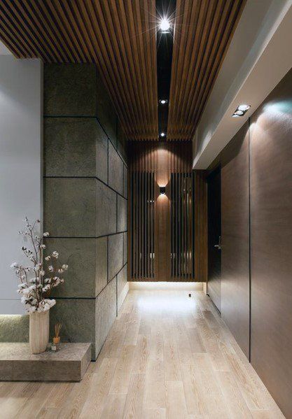 an empty hallway with wood paneling and lights on the ceiling is lit by recessed lighting