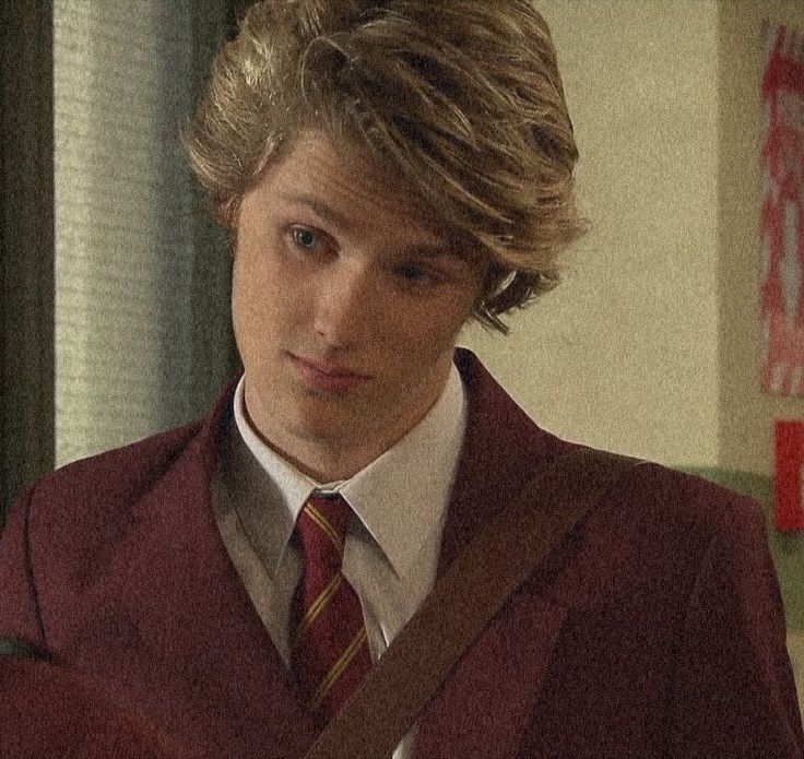 a young man with blonde hair wearing a red jacket and tie