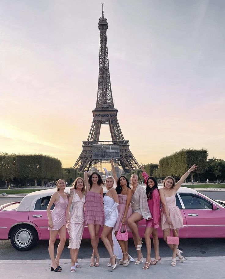 the girls are posing in front of the eiffel tower with their pink car