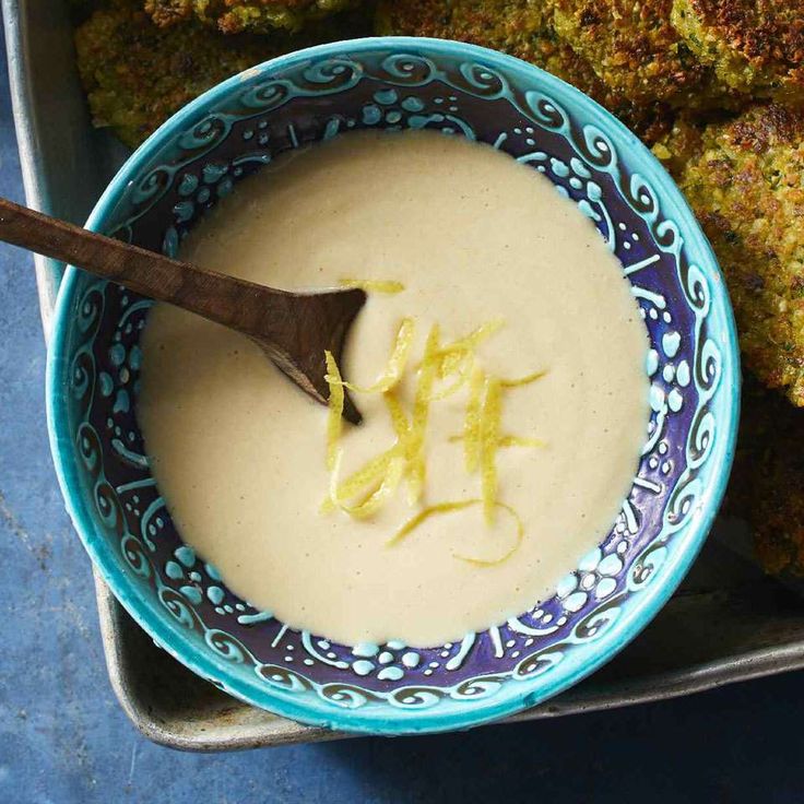 a blue and white bowl filled with broccoli florets next to a wooden spoon