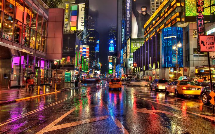 a city street filled with lots of traffic and tall buildings covered in neon colored lights