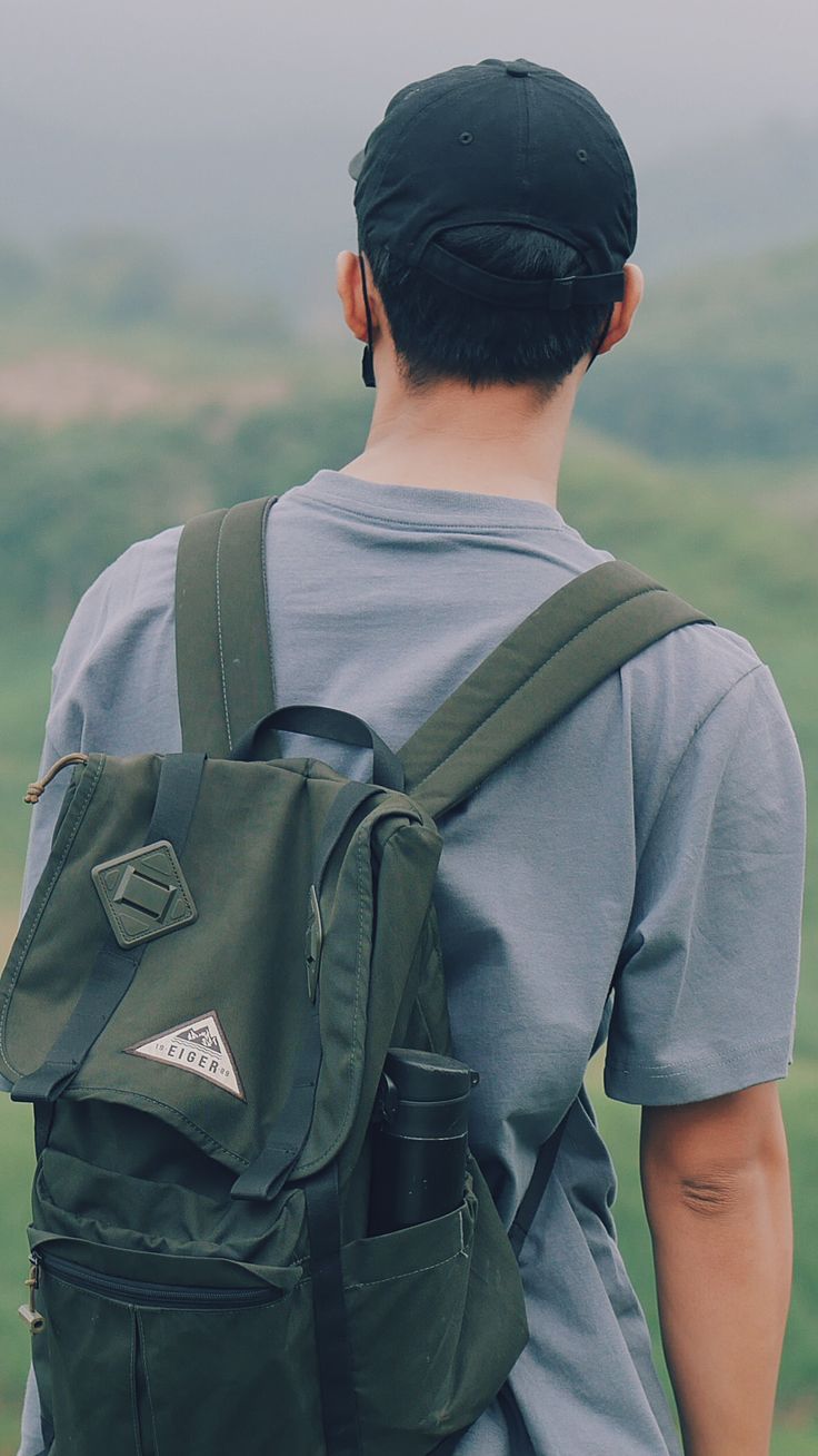 a man with a green backpack looking at the mountains